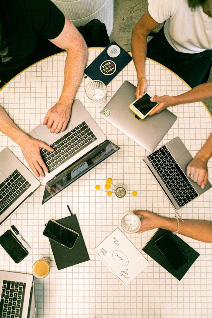 services-01 Top view of a team collaborating with laptops, phones, and notes in a modern office.